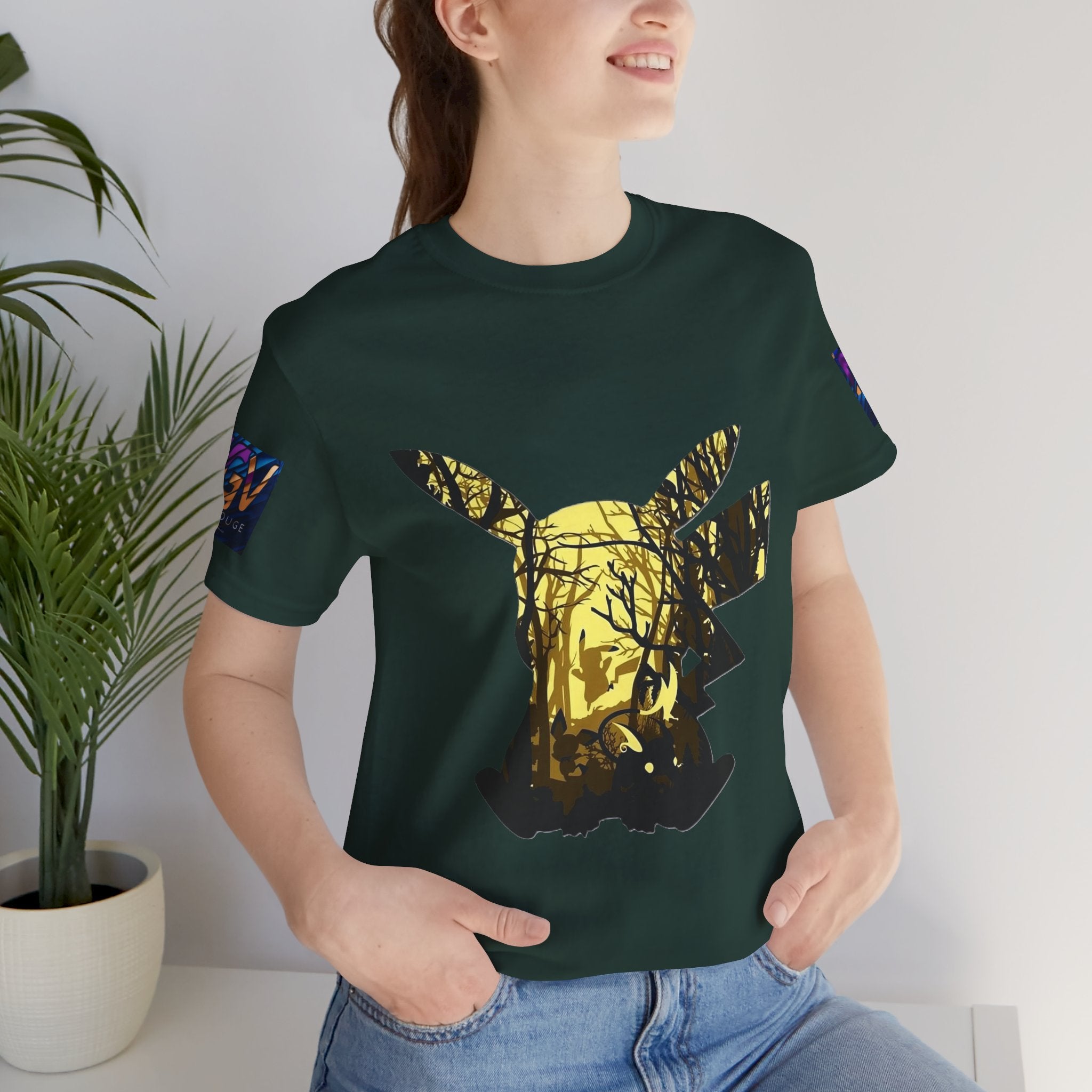 Person wearing a Black Heather t-shirt with a gold and black graphic design, standing indoors next to a plant.